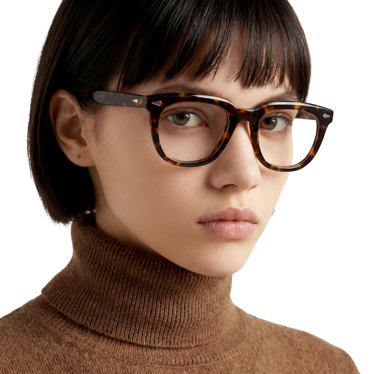 Person wearing tortoiseshell glasses with a plain background
