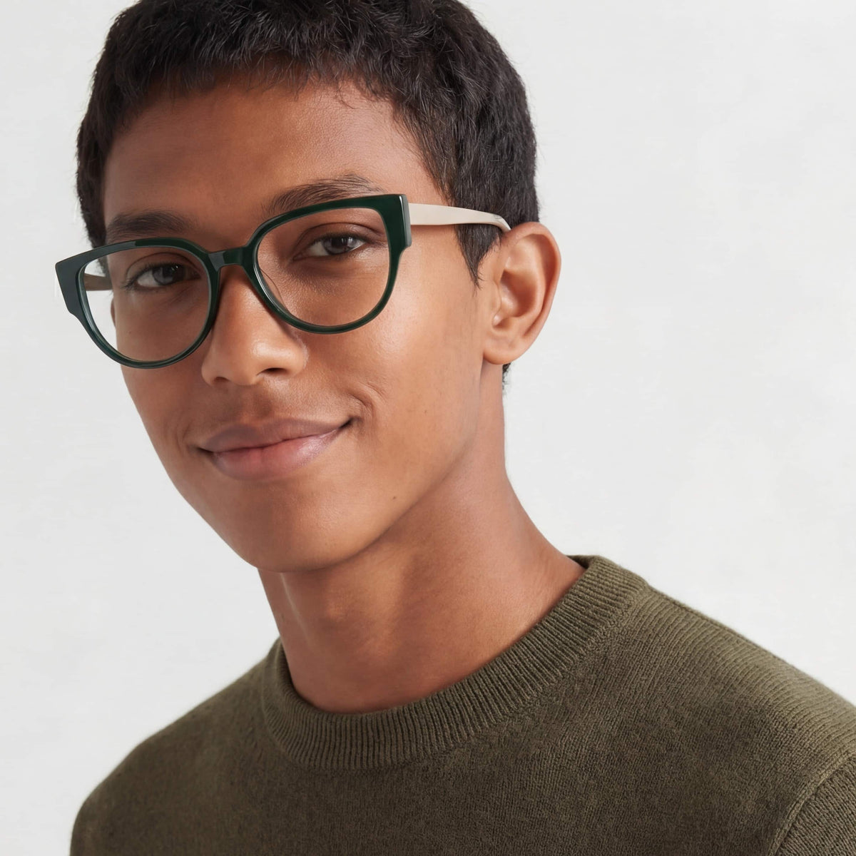 Person wearing green eyeglasses with a plain background