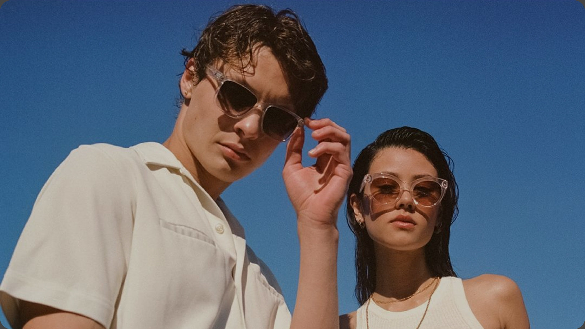 Two people wearing sunglasses against a clear blue sky