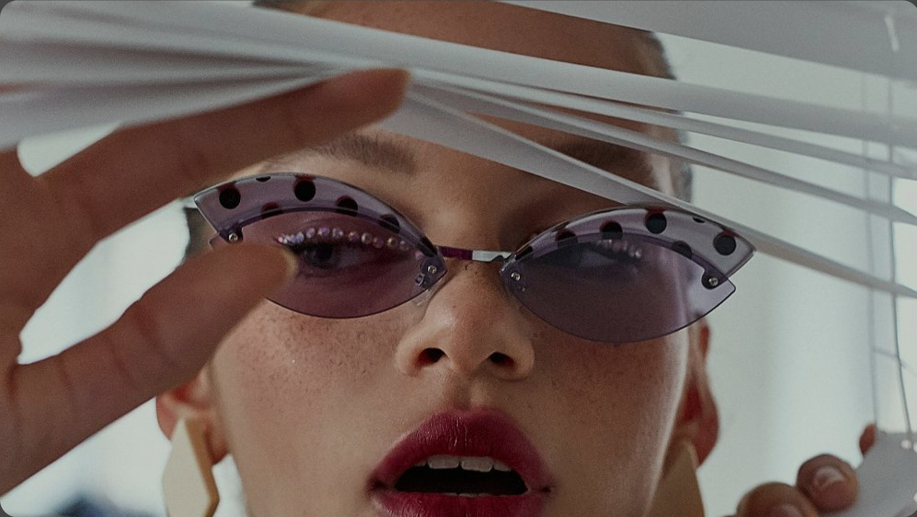 Close-up of a person wearing futuristic sunglasses with a white object in front of their face.