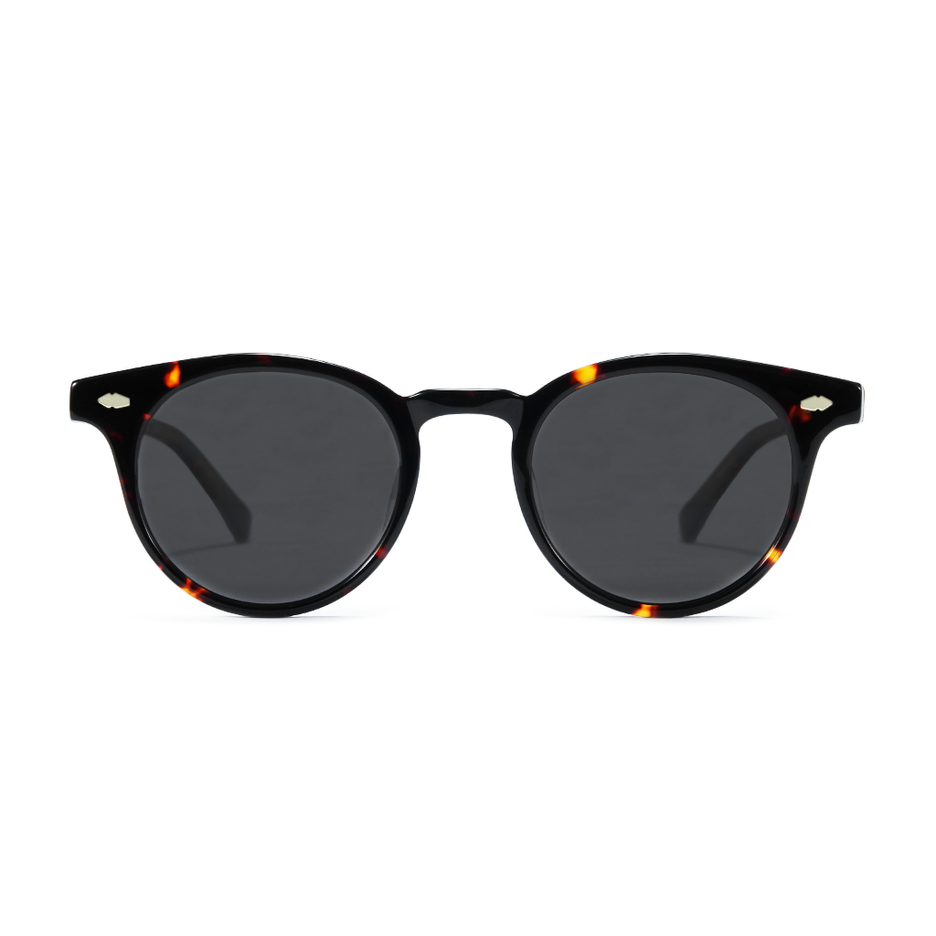 Round sunglasses with a glossy black acetate frame, subtle tortoiseshell patterns at the corners, and dark gray lenses.
