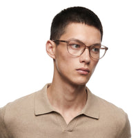 Person wearing glasses and a beige shirt on a white background