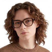 Person wearing glasses and a brown sweater on a white background