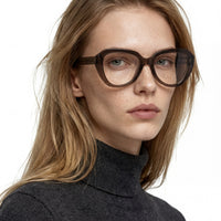 Woman wearing brown glasses with a neutral background