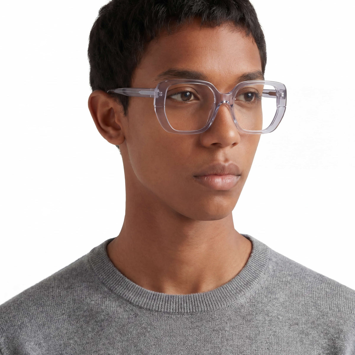 Person wearing clear glasses and a gray sweater on a white background