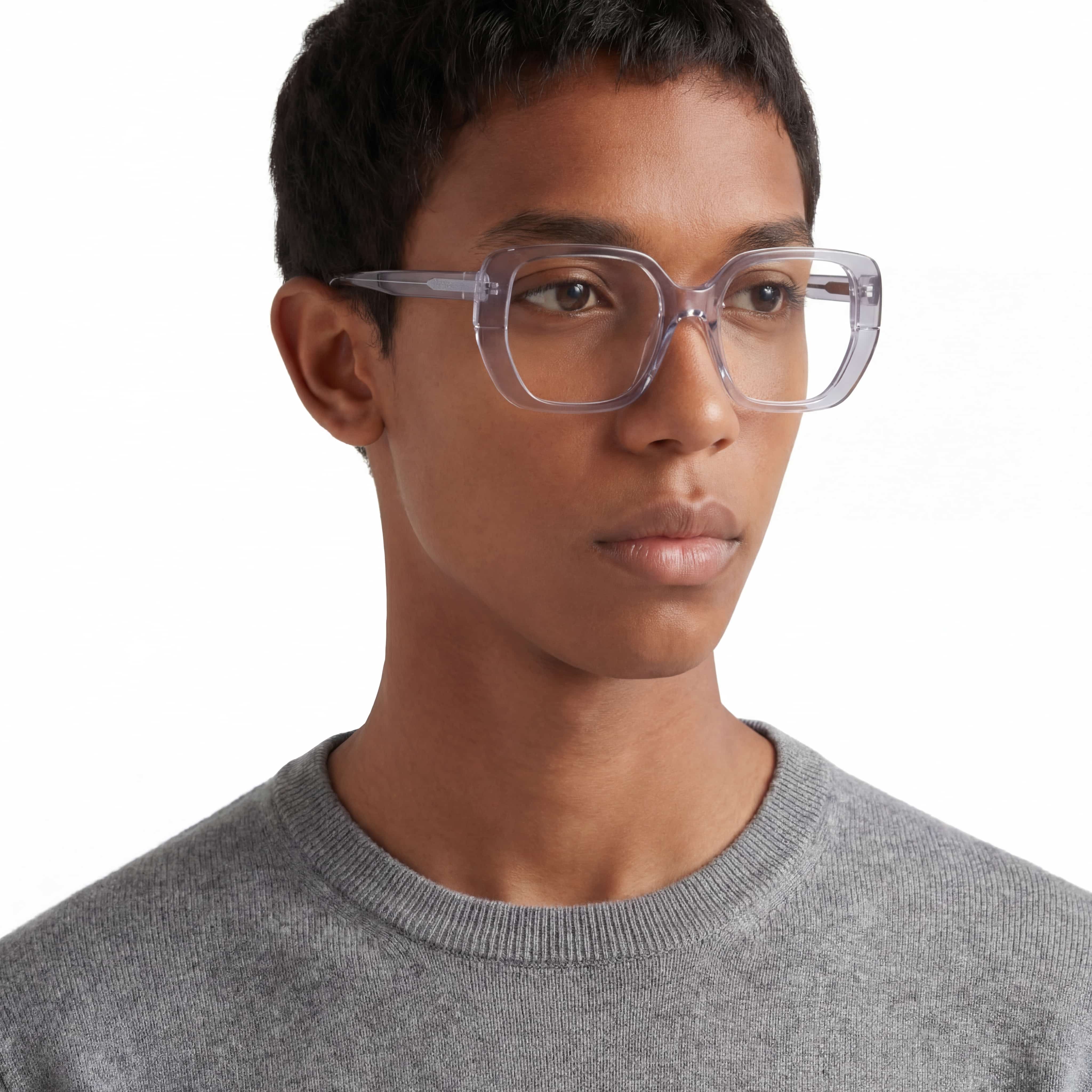 Person wearing clear glasses and a gray sweater on a white background