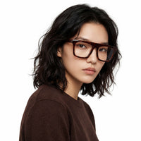 Person wearing glasses and a brown sweater on a white background