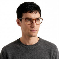 Man wearing glasses and a gray sweater on a white background