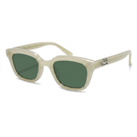 A pair of sunglasses with a translucent cream-colored acetate frame and dark green lenses, shown on a clean white background.