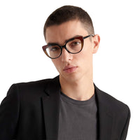 Person wearing a black jacket over a gray shirt with a plain background