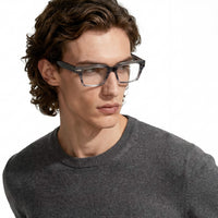 Man wearing glasses and a gray sweater on a white background