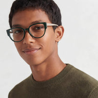 Person wearing green eyeglasses with a plain background