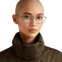 Person wearing glasses and a dark green coat on a plain background