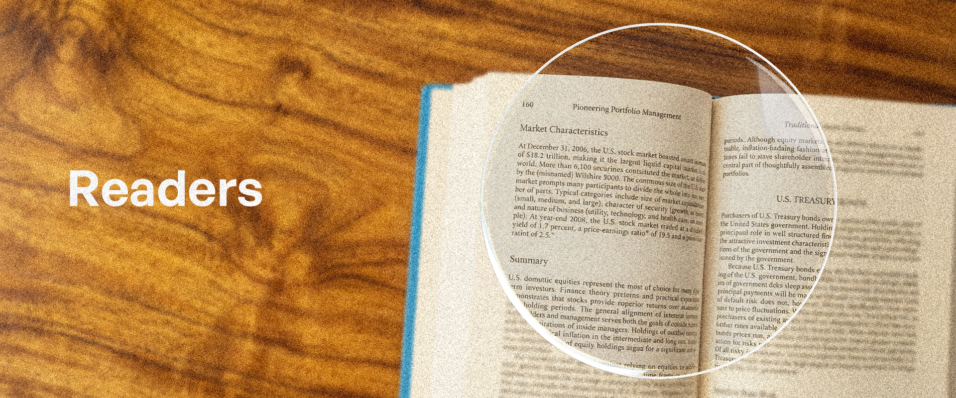 Open book on a wooden surface with the word 'Readers' displayed.