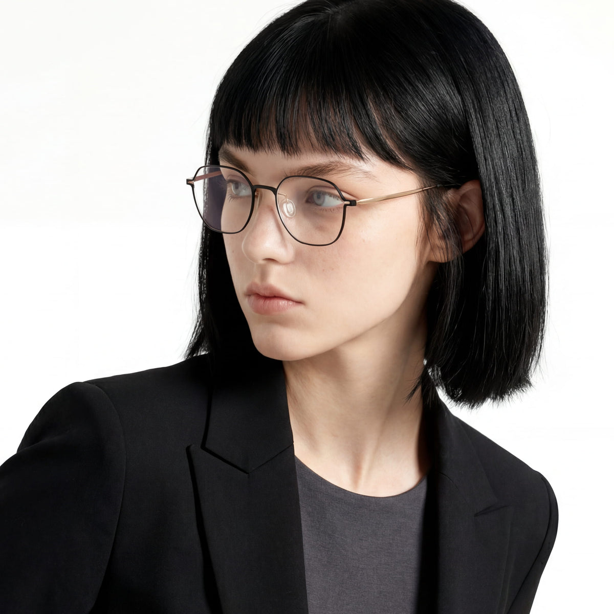 Person wearing glasses and a black blazer on a white background