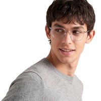 Man wearing clear glasses and a gray sweater on a white background