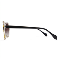 Side profile of a pair of sunglasses with a gold and black tortoiseshell frame, black temples, and dark lenses on a white background.