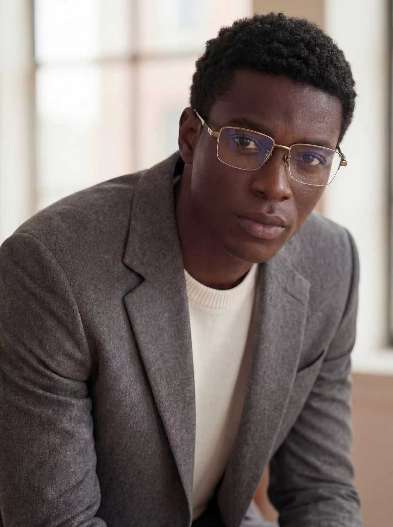 Man wearing glasses and a gray blazer in an indoor setting