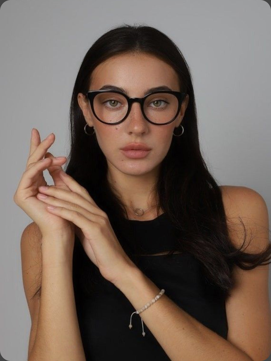 Woman wearing black glasses with a plain gray background