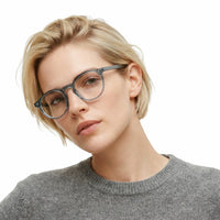 Woman wearing glasses and a gray sweater on a white background