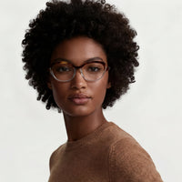 Woman wearing glasses and a brown sweater against a plain background