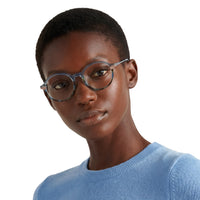 Person wearing glasses and a blue sweater on a white background