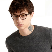 Person wearing glasses and a dark sweater on a white background