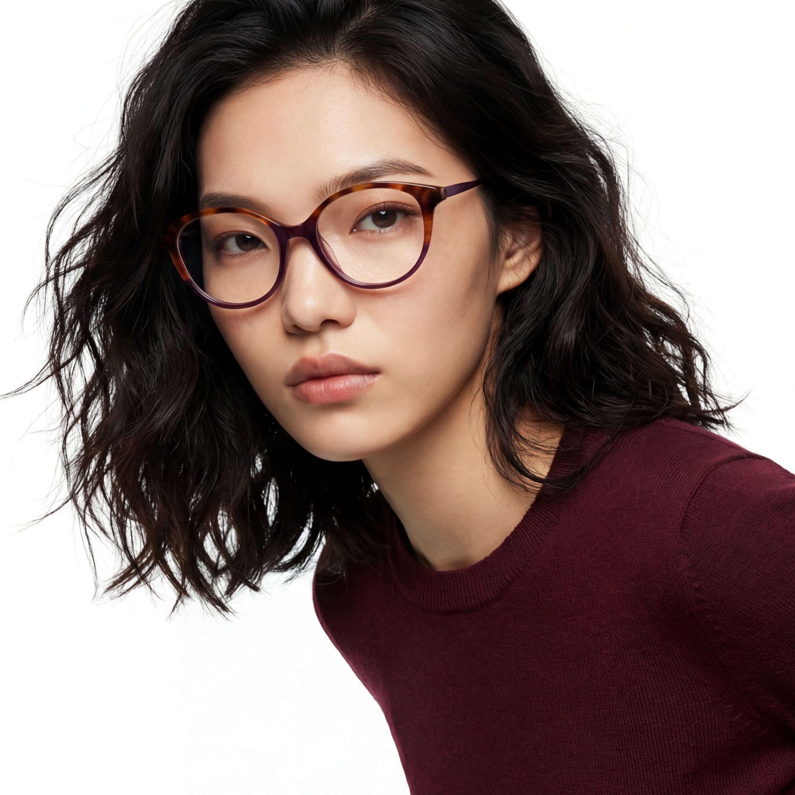 Woman wearing glasses and a maroon top on a white background