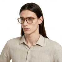 Person wearing glasses and a light-colored shirt on a white background