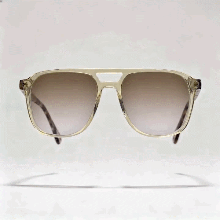Transparent light yellow double-bridge aviator acetate sunglasses frame with gradient brown tint lenses, marbled dark tortoise temple arms, light gray studio background