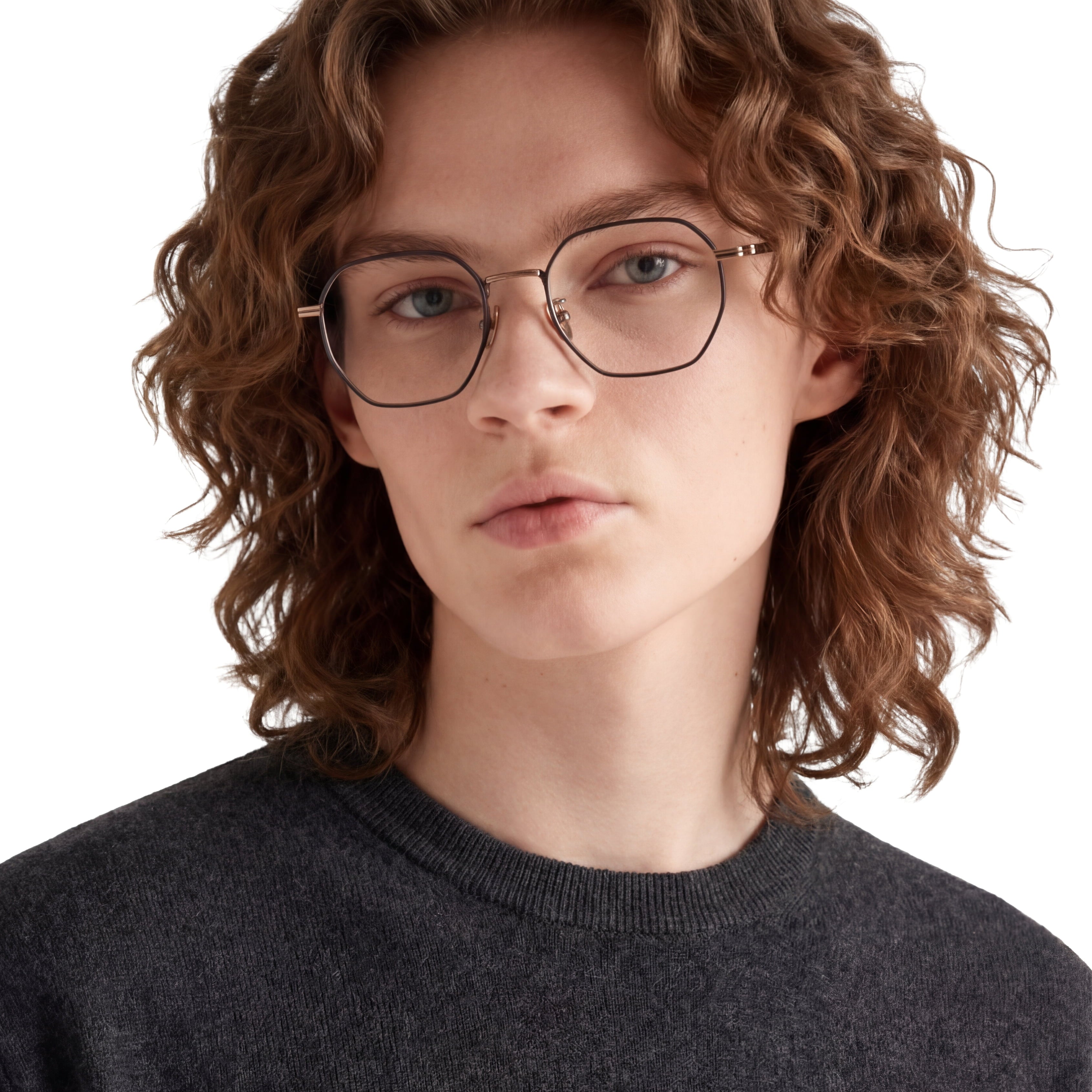 Person with curly hair wearing glasses and a dark sweater on a white background