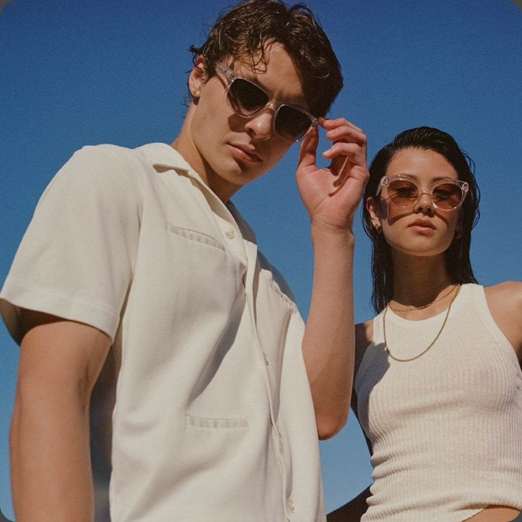 Two people wearing sunglasses against a clear blue sky.